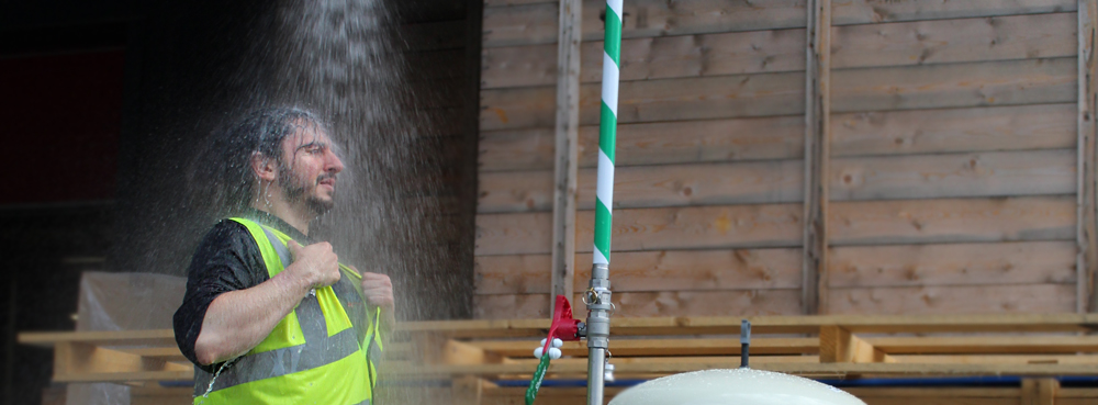 worker in high vis standing under an activated mobile safety shower