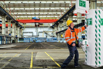 Worker in warehouse running to use Hughes temperature controlled safety shower