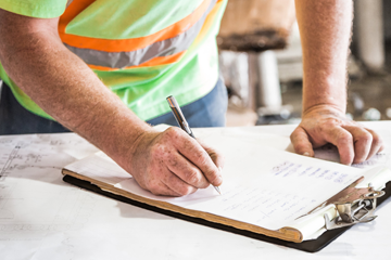 Worker in high vis writing on a clipboard