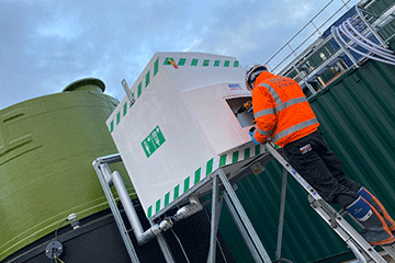 A Hughes Safety Showers engineer carries out regular maintenance work on an enclosed safety shower and eye wash unit