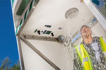 male worker in high vis in an activated emergency tank shower