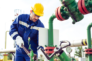 Worker in hard hat working on site using a wrench on pipework