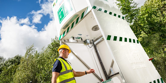 Worker walking into a Hughes emergency tank shower 