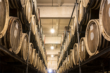 Wooden whisky barrels ageing in distillery storage area