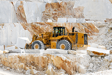 Heavy duty vehicle transporting marble block across quarry