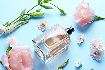 Full perfume bottle set among pink flowers against a blue background