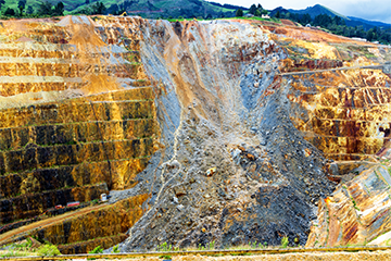 Open air gold mine with pathways carved out for heavy machinery and vehicles