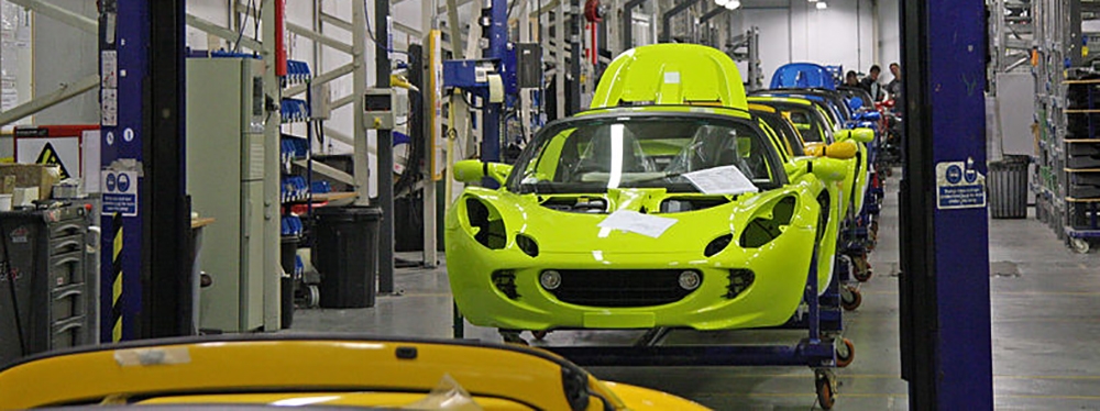 Car manufacturing production line with brightly coloured bodies of vehicles 