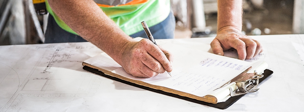 Worker in high vis writing on clipboard