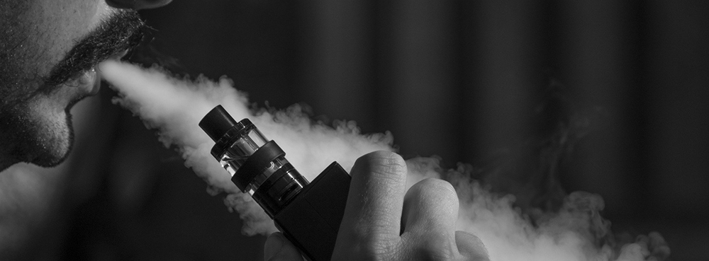 a man blowing a cloud of vapour and holding a vape