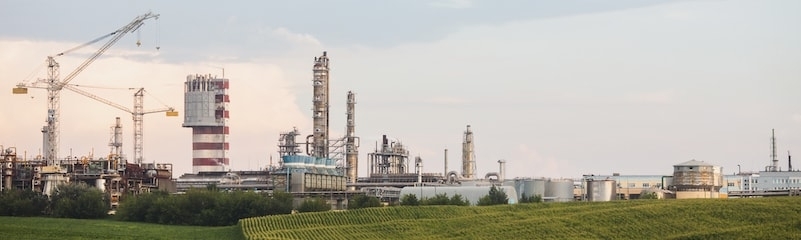 fertiliser plant with small hills shown in foreground and cranes in background