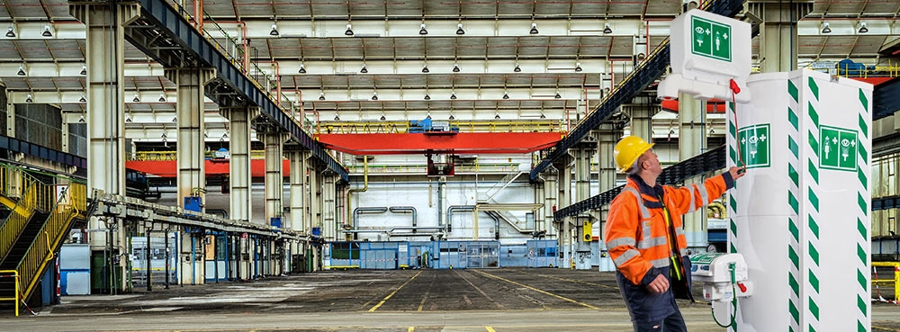 Worker in warehouse running to use Hughes temperature controlled safety shower